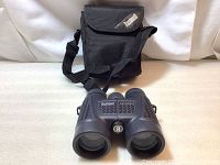 Black Bushnell binoculars with carrying case visible in the background, showing overall condition and included items.