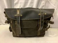 Front view of the brown National Geographic Africa Camera Satchel S showing canvas body with leather flap and strap closures.