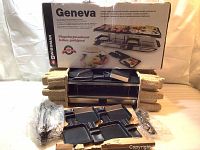 Full view of Swissmar Geneva raclette grill box and unboxed contents including raclette pans and power cord.