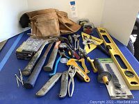 Wide view of assorted hand tools and Husky leather tool belt on blue surface