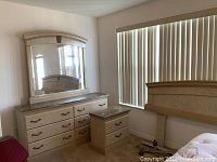 Close-up of dresser with mirror reflecting the headboard, showing drawer handles and marble/laminate top.