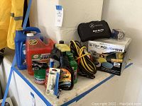 Full view of assorted car care and cleaning products including polisher box, jumper cables, and sprays