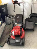 Frontal view of red mower with detached dust blocker bag in garage setting