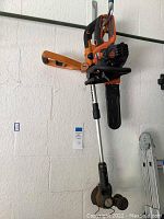 Worx gas-powered string trimmer and Black & Decker chainsaw hanging on a wall, showing overall condition and items included