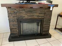 Front view of the faux stone electric fireplace showing full fireplace with faux stone surface and wooden mantel.