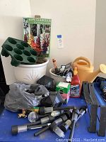Overview of the gardening supplies including plant pots, watering can, gloves, solar lights, and gardening accessories on a blue surface.