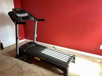 Gold's Gym Air Stride Plus treadmill full view in room with red wall and carpeted floor.