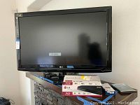 Photo showing LG 53-inch Full HD TV with remote, LG Blu-Ray player box and other accessories on table.