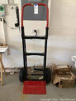 Full view of the Milwaukee hand truck dolly showing red handle and toe plate, black frame, and wheels