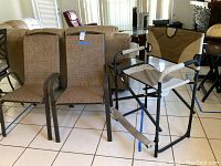 Set of two sling patio chairs and one folding camp chair with table displayed indoors on tiled floor.