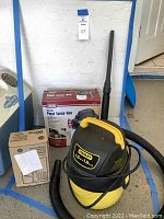 Wide view of lot showing Stanley vacuum, paint spray gun in box, and AC disconnect in box