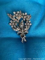 Front view of brooch on blue fabric background