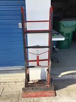 Front view of red metal appliance dolly showing rust and scratches on frame and loading lip.