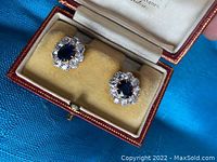 Earrings in open red leather jewelry box with yellow velvet interior viewed from above