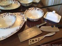 Photo showing large ceramic platter and two matching bowls with floral design and three knives