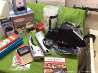 Photo showing assortment of various used kitchen tools including graters, hand mixers, and accessories arranged on green towel.