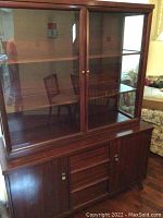 Front view of the mid-century wooden hutch showing upper glass display cabinet with two doors and lower storage cabinet with two doors and center section.