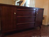 Front view of wood sideboard showing three central drawers and side cabinets