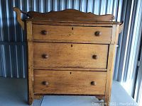 Front view of washstand showing three drawers with wooden knobs and keyholes.