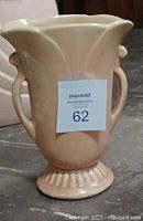 Photo of beige ceramic vase with curved handles and flared top
