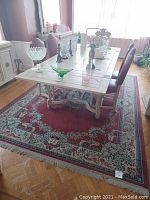 Photo of the dining room rug laid underneath a dining table with chairs, showing the design and size in context.