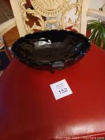 Photo of large black glass bowl showcasing shape and scalloped edges on a red surface