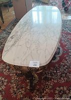 Top view showing white marble oval table top with grey veining.