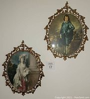 Two oval framed portrait paintings of a man and a woman hanging on a wall.
