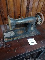 Side view of vintage Singer sewing machine in black with gold detailing on the base, mounted on table with folding design visible