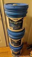 Three stacked 5-gallon blue pails with blue lids, showing the product label including brand and product name.