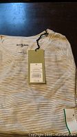 Folded men's long sleeve Goodfellow sweatshirt in light grey with thin horizontal stripes and visible hang tag with size M