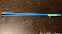Blue-coated hacksaw blades laid flat, showing one blade with green tape around one end and '12x1/2x24T' marked on it in black marker.