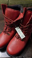 Front view of red leather Cougar boots with tags showing waterproof and temperature rating.