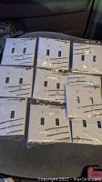 Ten white 2-gang wall plates in sealed plastic packaging, arranged in two rows.