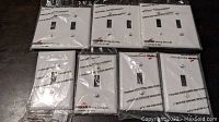 7 new white Cooper wall switch plates in packaging, 4 single-gang and 3 double-gang.