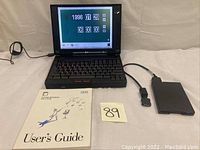 Wide view: open ThinkPad 365XD powered on showing date/time setup screen, external diskette drive and user’s guide laid out.