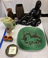Full lot image showing black nude lady sculpture, Francoma teapot, vases, ashtrays and decorative plate with horse and trees.