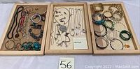 Three trays of mixed costume jewelry items including necklaces, bracelets, and earrings.