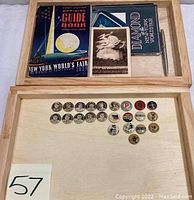 Two wooden trays showing guidebooks, postcard, pencil in upper compartment and cigarette pinback buttons in lower compartment