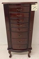 Front view of dark brown wooden jewelry armoire with eight drawers and side doors closed
