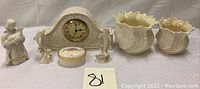 Full lot showing porcelain clock with dolphins, trinket box, dolphin figurines, Belleek vases, and nativity figure, all in cream and white with gold accents