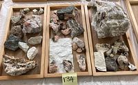 Wide view of multiple mineral rocks arranged on three wooden trays, various colors and textures visible