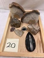 Wide shot showing full collection of mineral rocks, fossils, and sliced geodes on wooden tray.