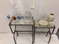 Photo of metal framed mirrored top tables with glassware and ceramic items on display