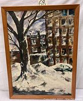 Full view of oil on canvas painting showing winter street scene with tree and buildings framed in wood.