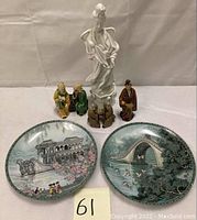 Full view of the two collectible plates with detailed Eastern architecture and nature scenes, along with six assorted Chinese figurines.