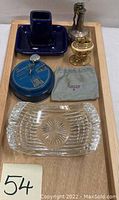 Full view of lot including three Ronson lighters, Waterford ashtray, blue ashtray, mechanical bank, and Ronson cloth