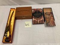 Photo showing the Lilka Classica pipe in its satin-lined wooden box alongside two wooden cigar boxes and two cigar-related books/boxes.