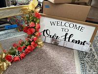 Mirror with greyish frame, gold bead trim, decorated with red roses and gold flowers on one side, placed on carpet near boxes