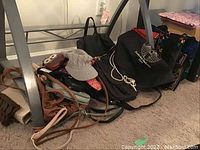 Photo of multiple handbags and purses arranged under a table, showing various styles and colors.